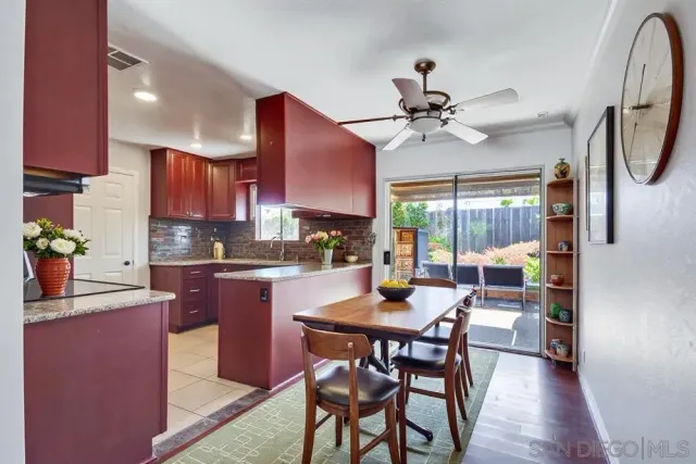 a kitchen with stainless steel appliances granite countertop a stove a refrigerator a sink a dining table and chairs with wooden floor