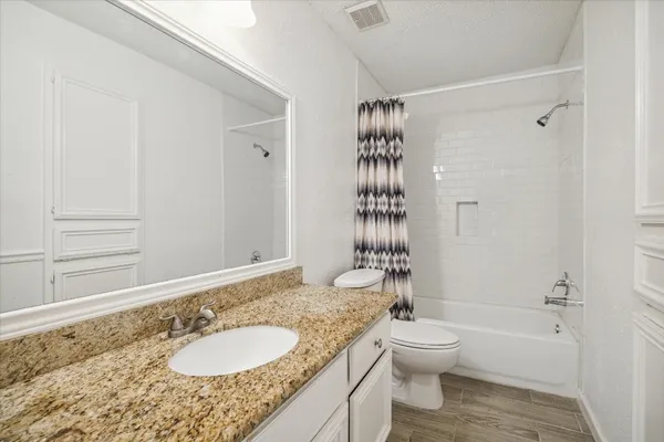 a bathroom with a granite countertop sink toilet a mirror and shower