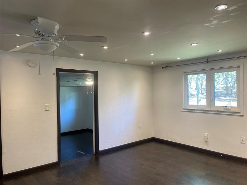 10140 Lake Louisa Road, Unit A Clermont, FL 34711 - Photo 6 of 18 an empty room with wooden floor and fan