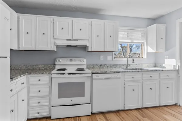a kitchen with granite countertop white cabinets and white appliances