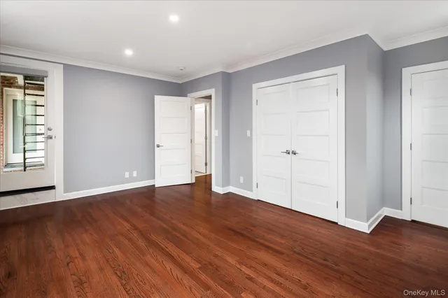 an empty room with wooden floor & closet area