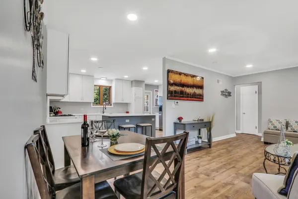 a kitchen with stainless steel appliances granite countertop a table chairs sink and cabinets