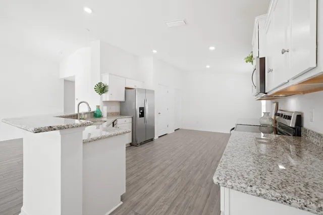a kitchen with granite countertop a stove a sink and a microwave