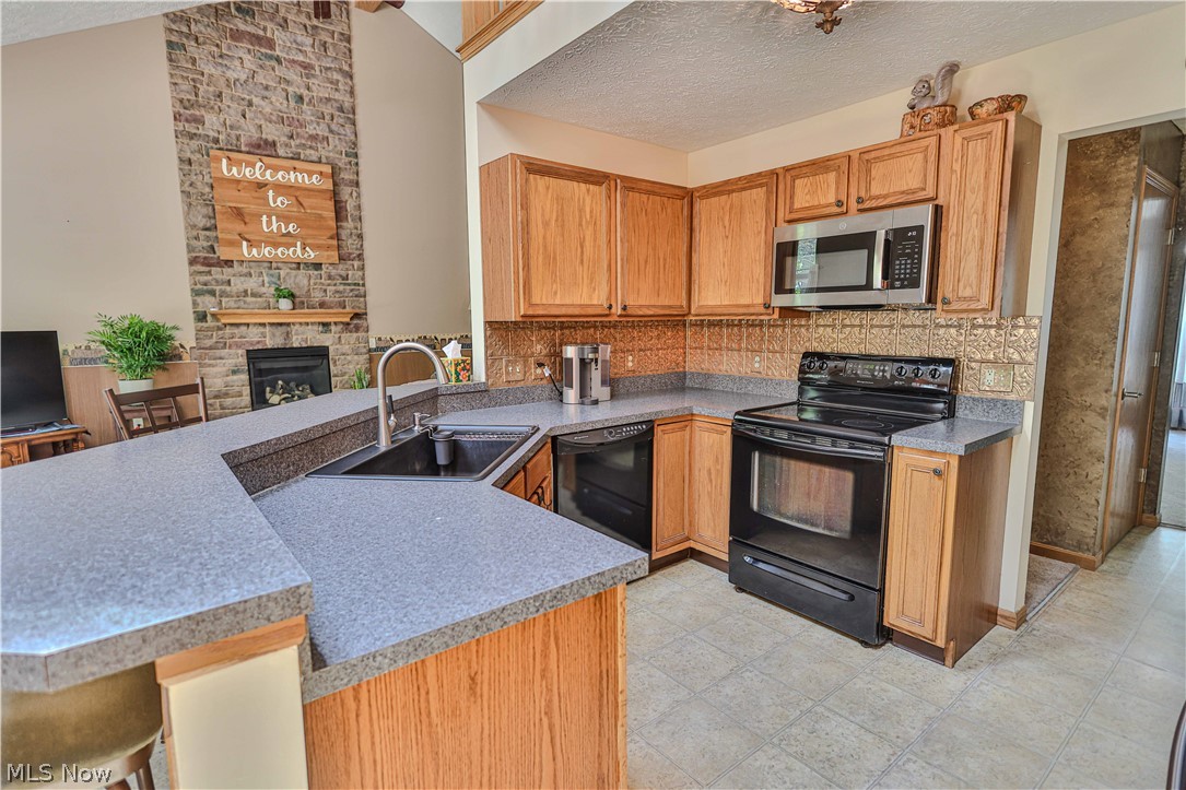 11154 Johnsford Road Southwest Beach City, OH 44608 - Photo 27 of 50 Kitchen featuring wood cabinetry, stone-finish countertops, and black appliances including a range and dishwasher