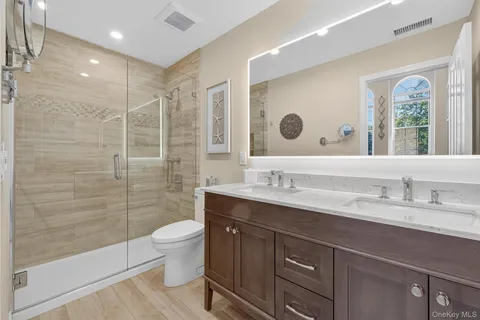 a spacious bathroom with a granite countertop sink a toilet a mirror and a shower