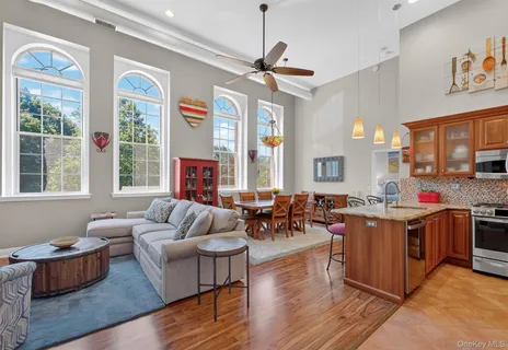 a living room with furniture kitchen view and a large window