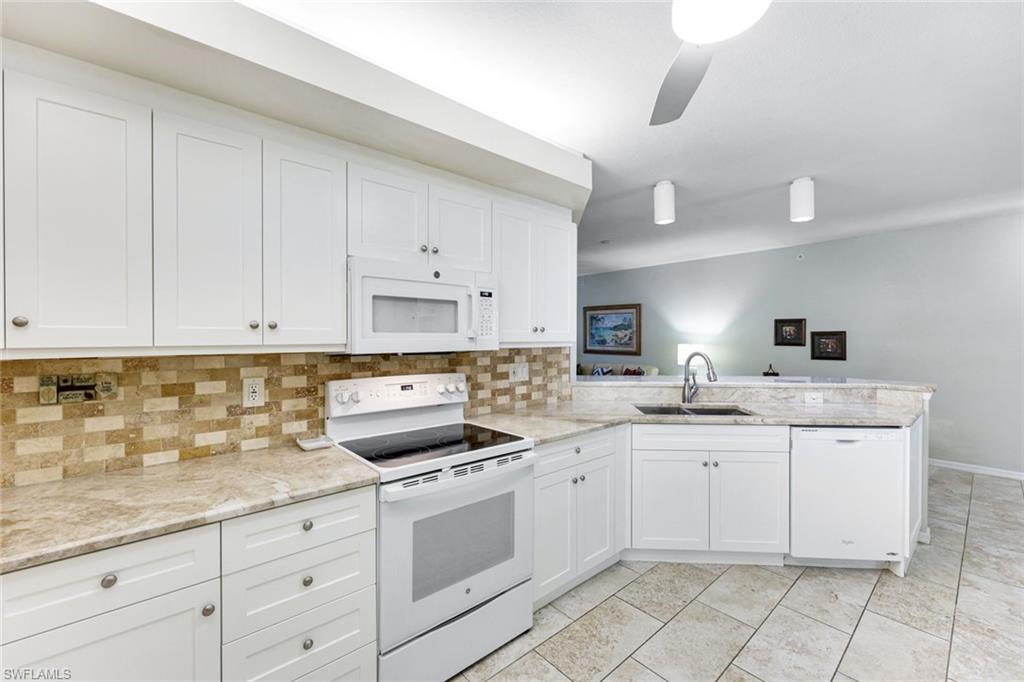 23861 Costa Del Sol Road, Unit 103 Estero, FL 34135 - Photo 4 of 29 a kitchen with white cabinets sink and white appliances