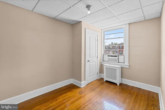 an empty room with wooden floor and window