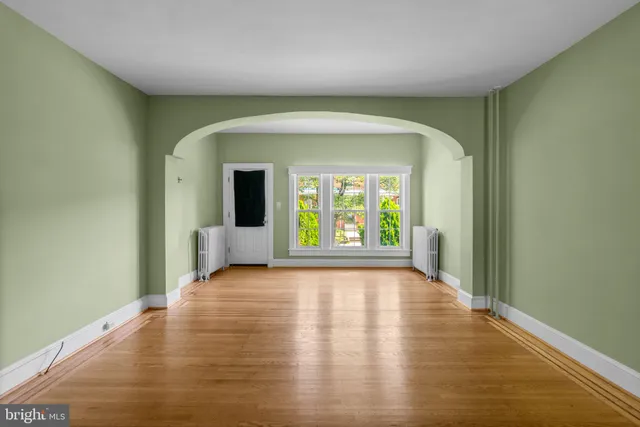 a view of an empty room with a window and wooden floor