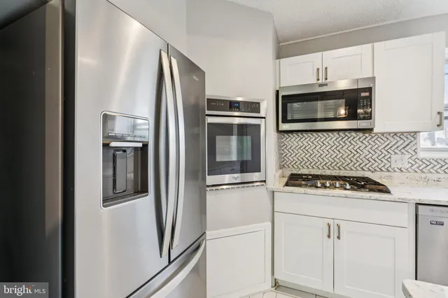a kitchen with white cabinets and stainless steel appliances