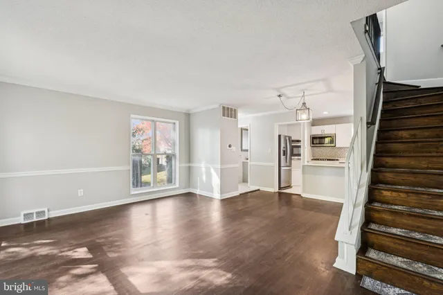 a view of a livingroom with wooden floor and stairs