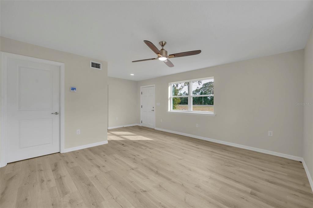 31201 Merry Road Tavares, FL 32778 - Photo 6 of 40 an empty room with wooden floor ceiling fan and windows