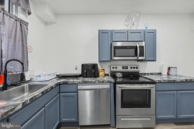 a kitchen with stainless steel appliances granite countertop a sink stove microwave and refrigerator
