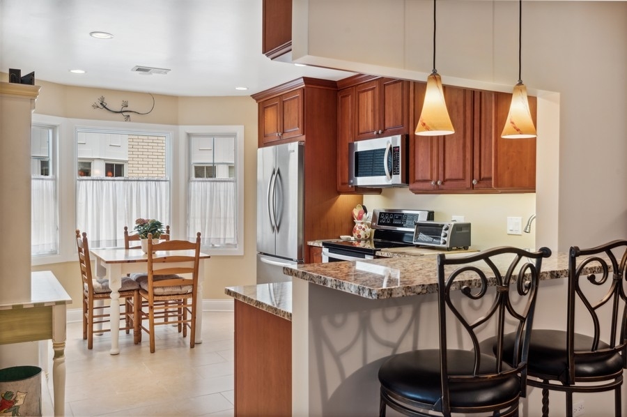 715 Ridge Road, Unit 3C Wilmette, IL 60091 - Photo 12 of 24 a kitchen with stainless steel appliances granite countertop a stove top oven a refrigerator a dining table and chairs with wooden floor