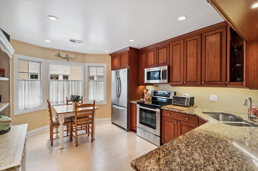 715 Ridge Road, Unit 3C Wilmette, IL 60091 - Photo 15 of 24 a kitchen with granite countertop wooden cabinets dining table and stainless steel appliances