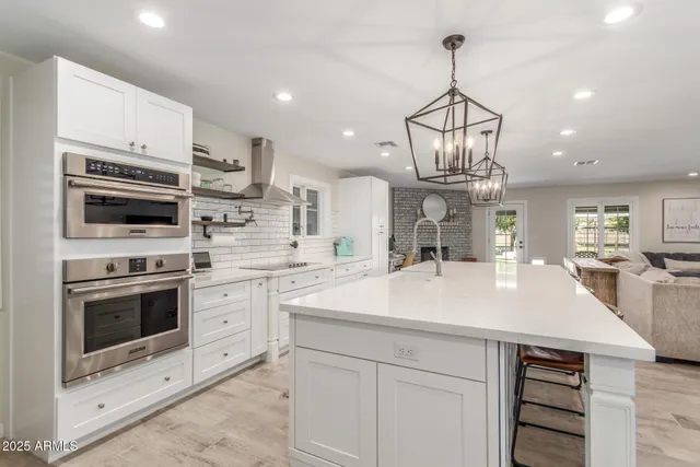 a kitchen with kitchen island granite countertop wooden cabinets and a chandelier