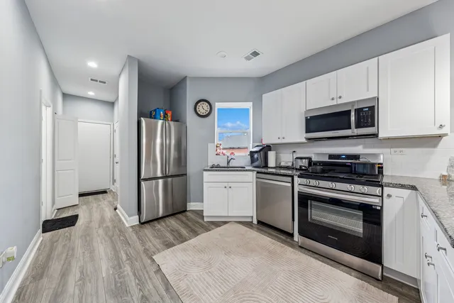 a open kitchen with stainless steel appliances granite countertop a refrigerator and microwave