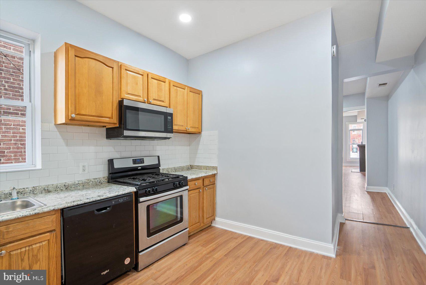 1604 North Broadway Baltimore, MD 21213 - Photo 16 of 39 a kitchen with stainless steel appliances granite countertop a stove a sink and a microwave