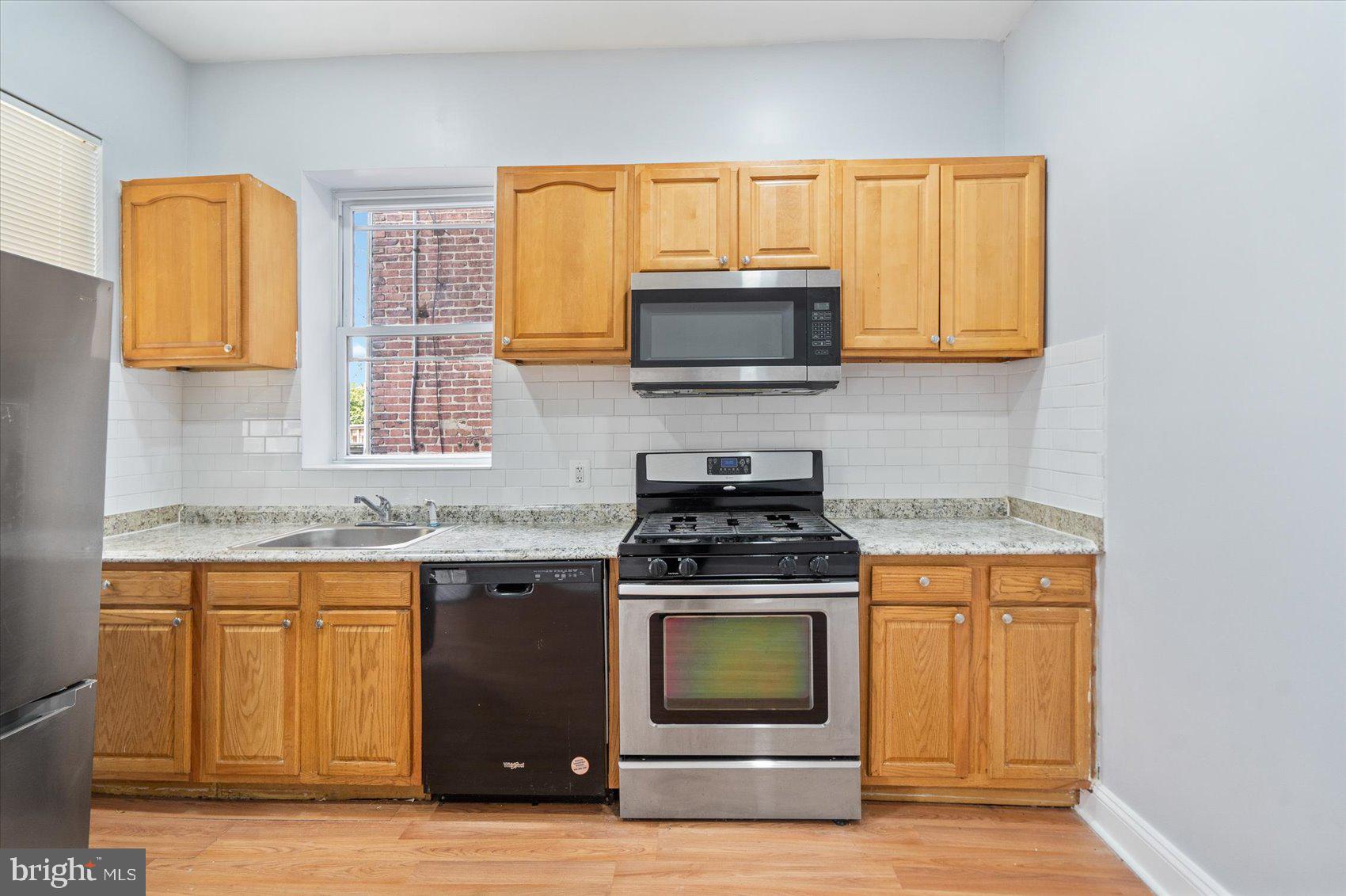 1604 North Broadway Baltimore, MD 21213 - Photo 17 of 39 a kitchen with stainless steel appliances granite countertop a stove a microwave and a sink