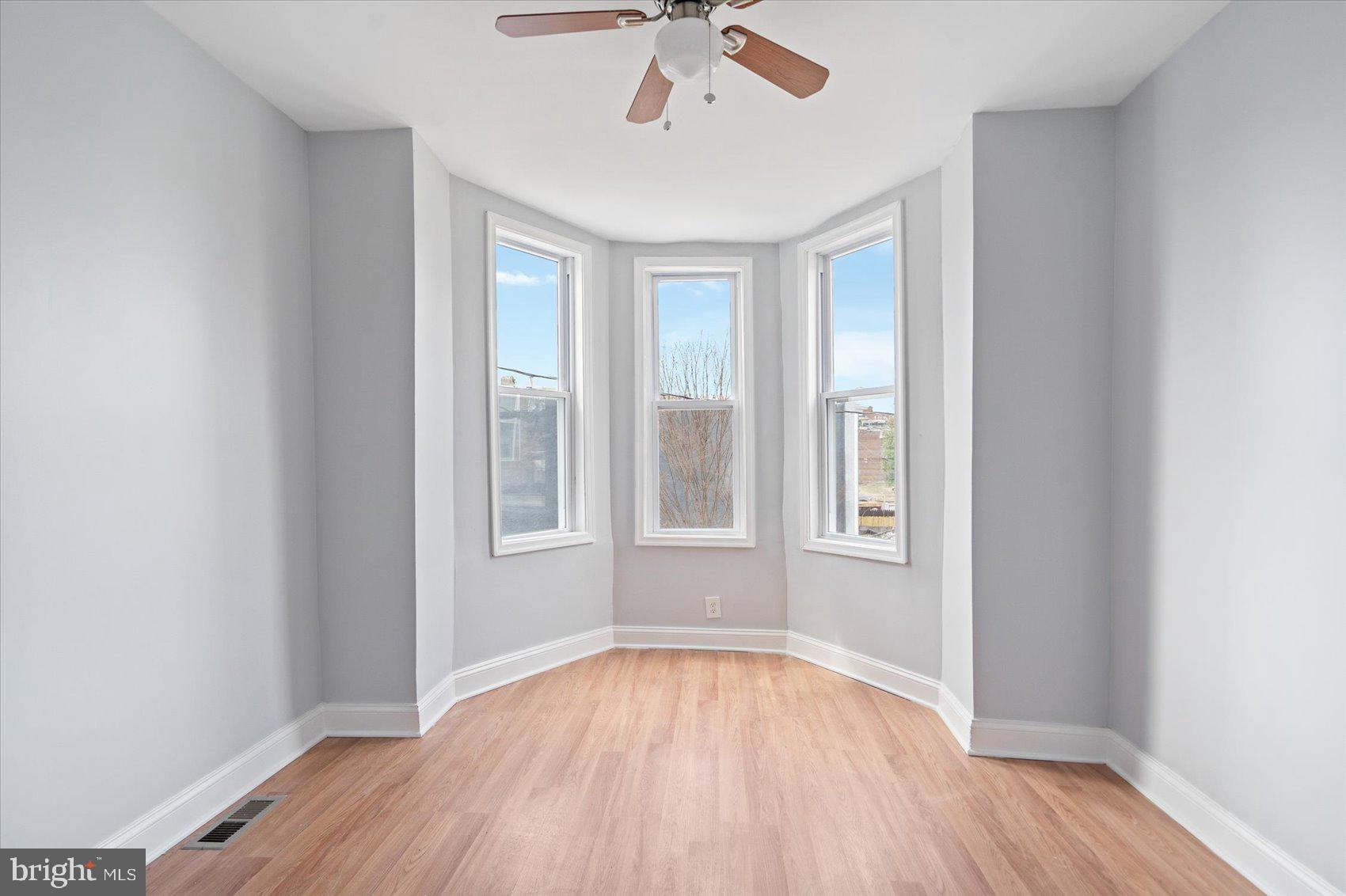 1604 North Broadway Baltimore, MD 21213 - Photo 27 of 39 an empty room with wooden floor chandelier fan and windows