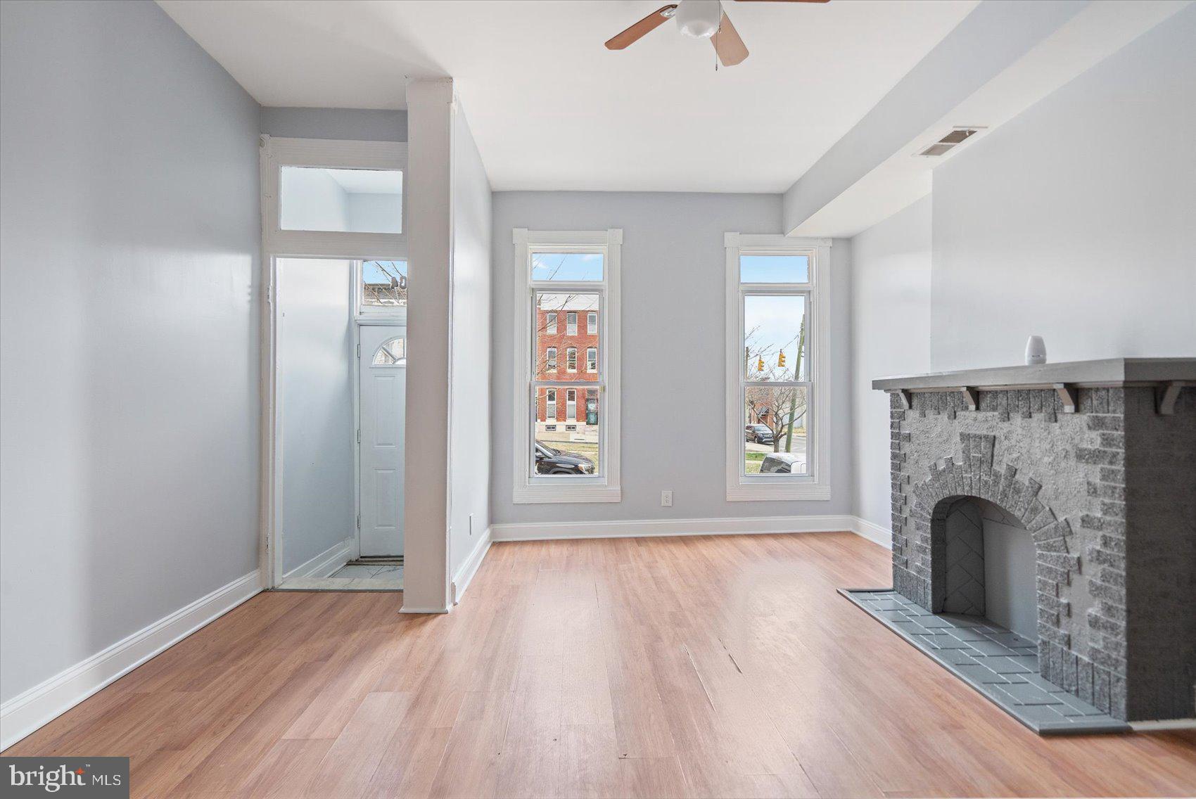 1604 North Broadway Baltimore, MD 21213 - Photo 6 of 39 an empty room with wooden floor fireplace and windows