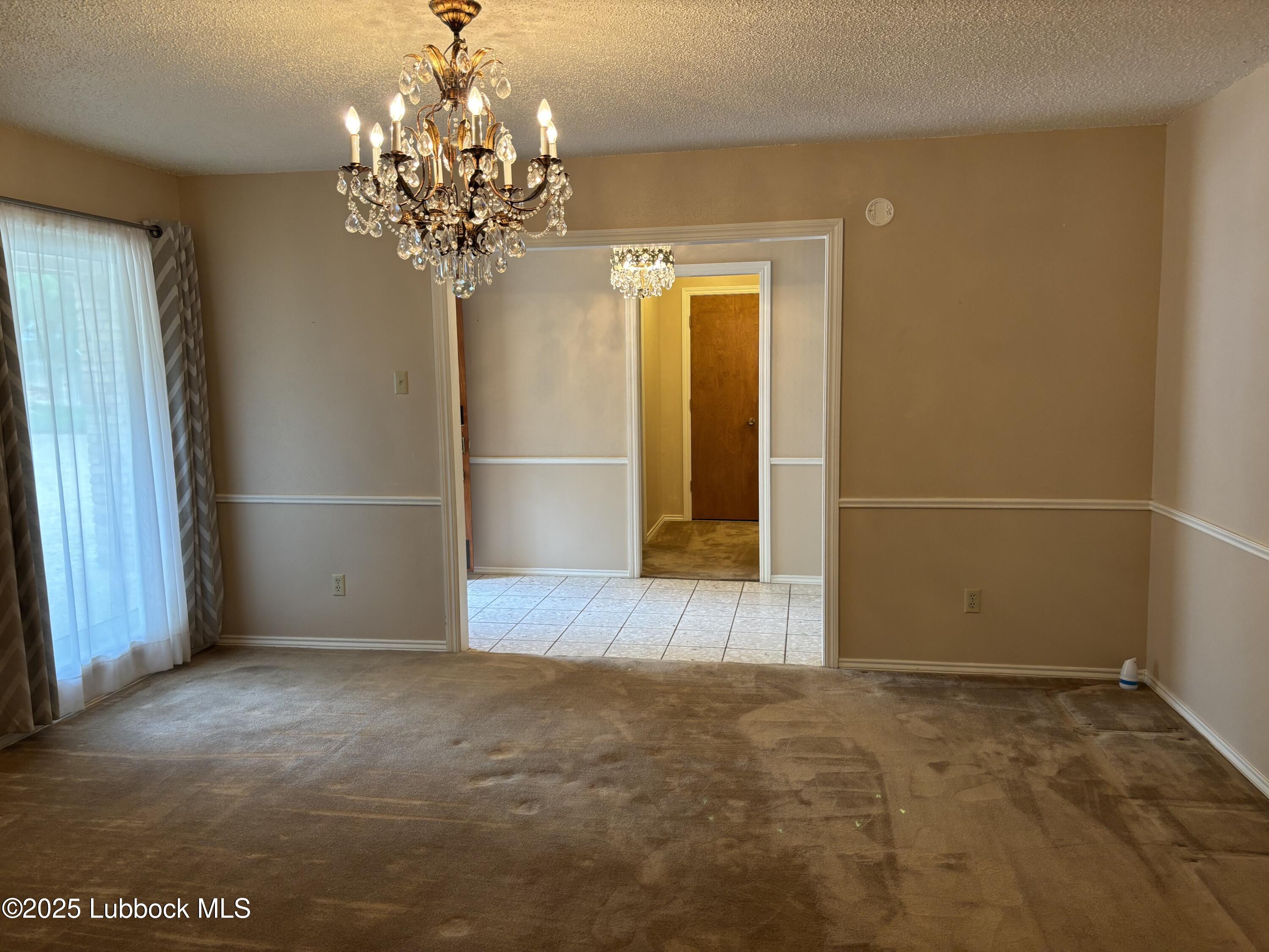 53 East Lakeshore Drive Ransom Canyon, TX 79366 - Photo 15 of 43 an empty room with wooden floor and chandelier