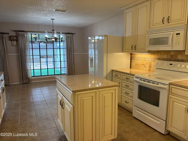 a kitchen with granite countertop white cabinets and white appliances
