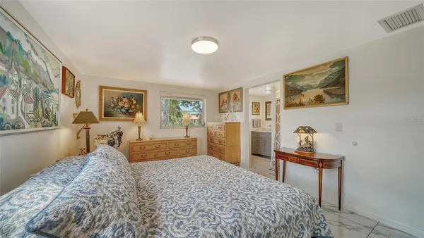 a bedroom with a bed and a lamp on dresser