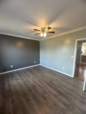 an empty room with wooden floor and fan