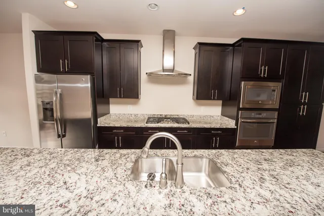 a kitchen with granite countertop a refrigerator and a stove top oven