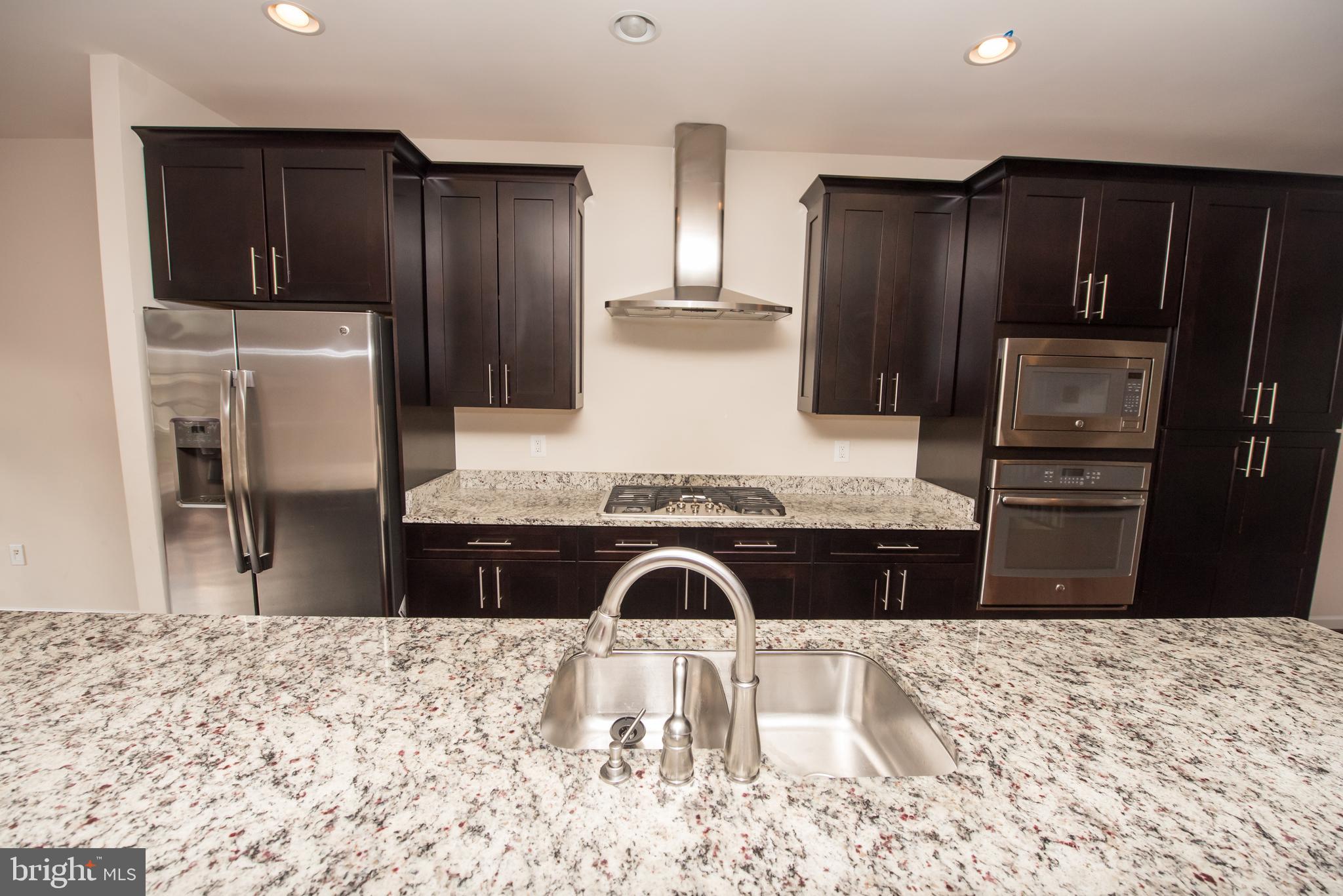 7444 Burnside Way Hanover, MD 21076 - Photo 3 of 46 a kitchen with granite countertop a refrigerator and a stove top oven
