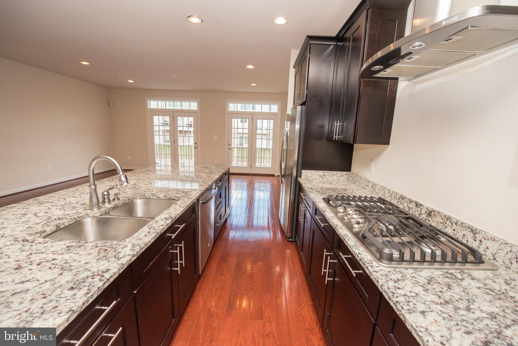 7444 Burnside Way Hanover, MD 21076 - Photo 9 of 46 a kitchen with kitchen island granite countertop a sink stove and refrigerator