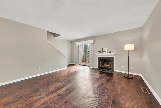 a view of an empty room with wooden floor fireplace and a window