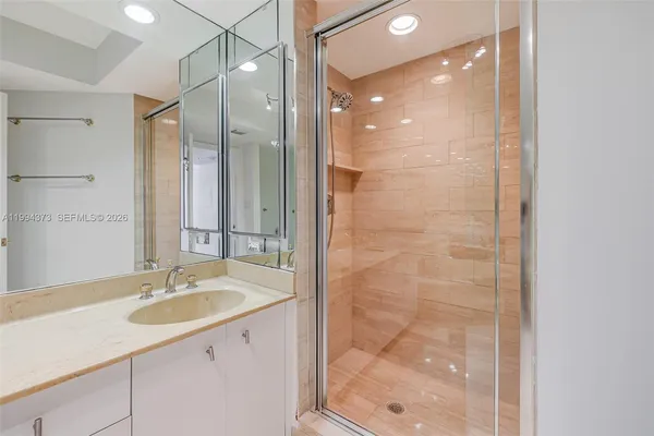 a bathroom with a granite countertop toilet sink shower and mirror