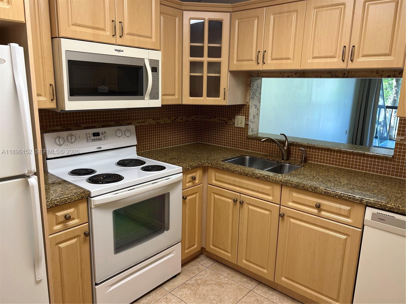 a kitchen with granite countertop white cabinets and white appliances