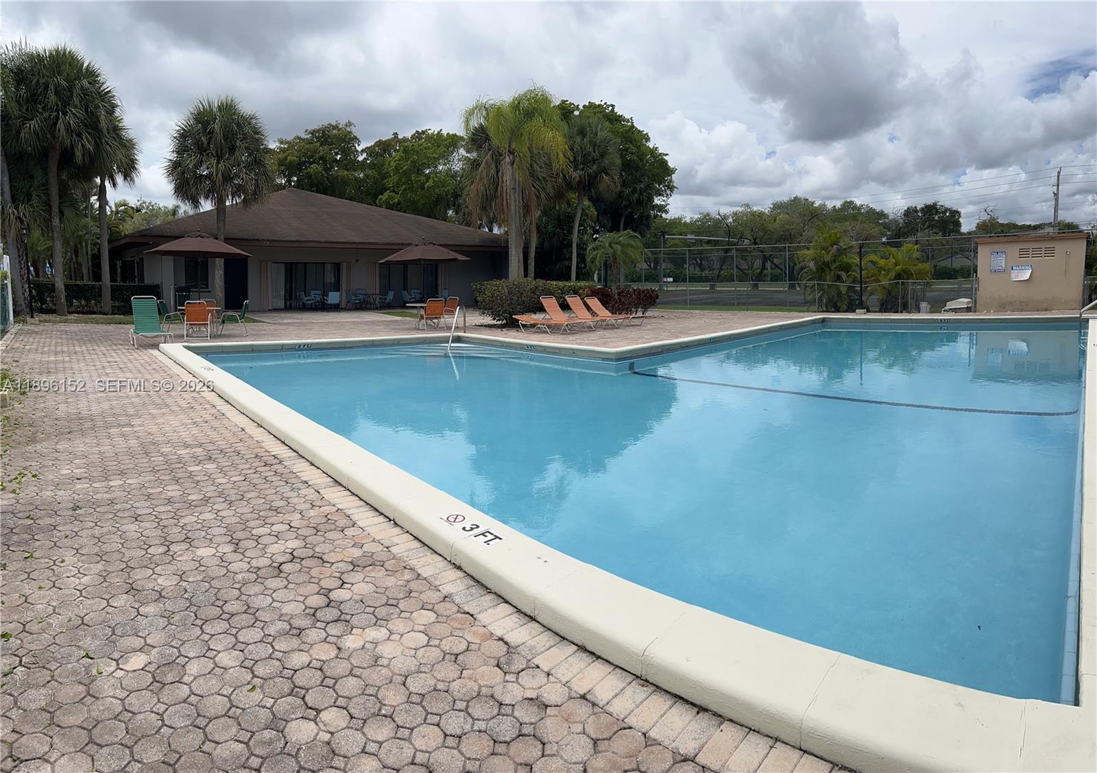 10855 Southwest 112th Avenue, Unit 215 Miami, FL 33176 - Photo 36 of 45 a view of a patio with swimming pool and table and chairs under an umbrella