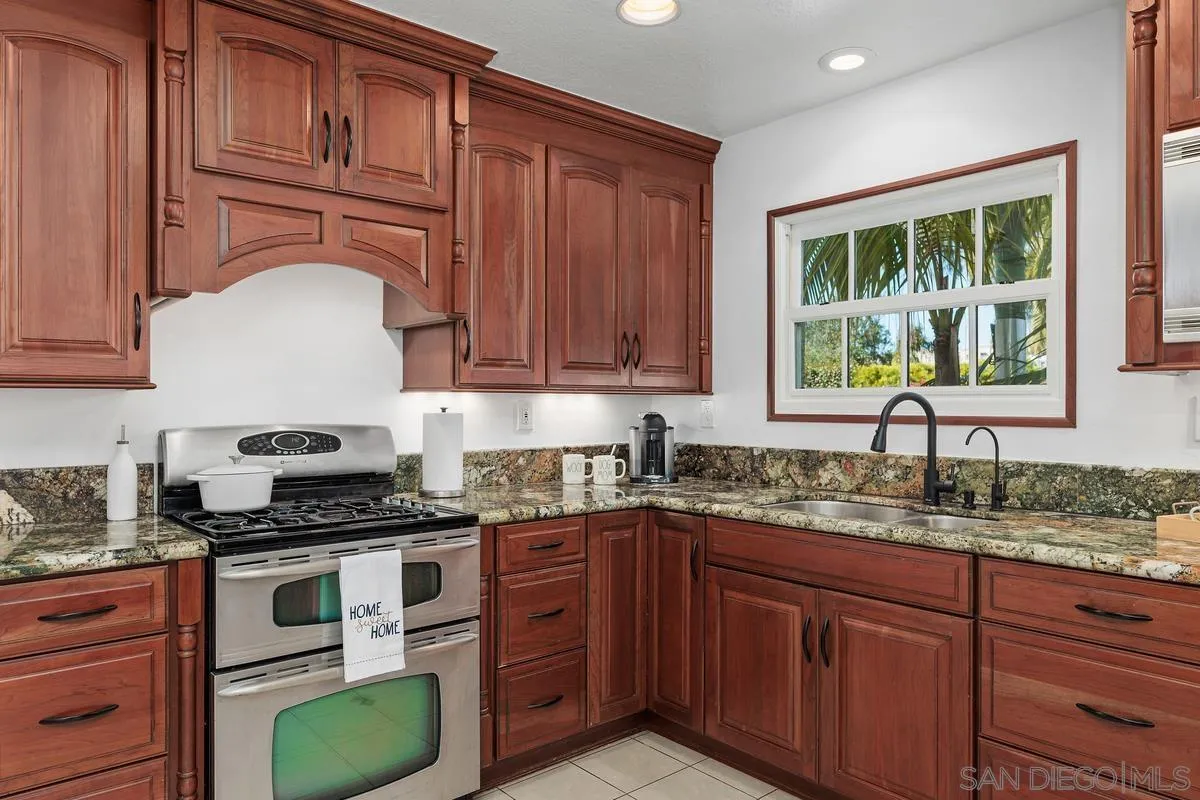 2016 Sequoia Street San Marcos, CA 92078 - Photo 19 of 50 a kitchen with granite countertop cabinets a sink a window and stainless steel appliances