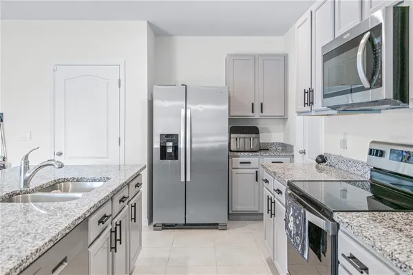 a kitchen with stainless steel appliances granite countertop a sink stove refrigerator and cabinets
