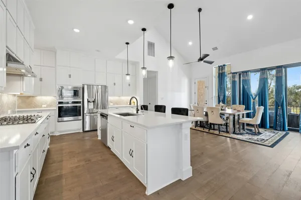 a large kitchen with stainless steel appliances kitchen island granite countertop a lot of cabinets and refrigerator