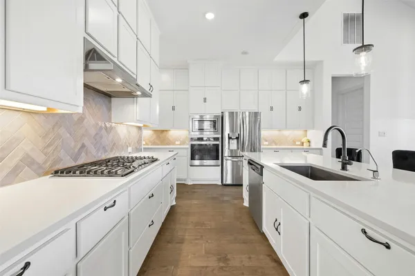 a kitchen with white cabinets a sink and appliances