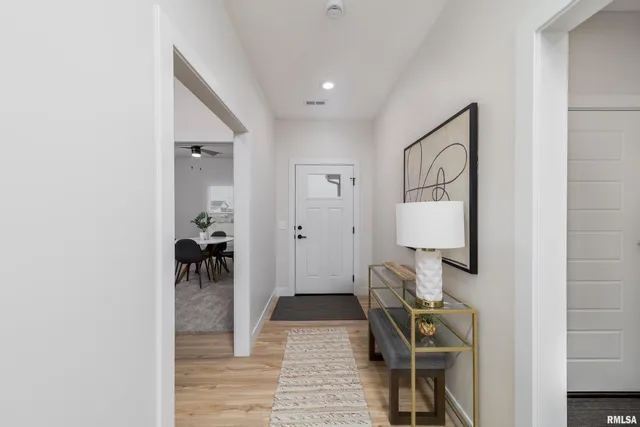 a view of a hallway with wooden floor and a living room