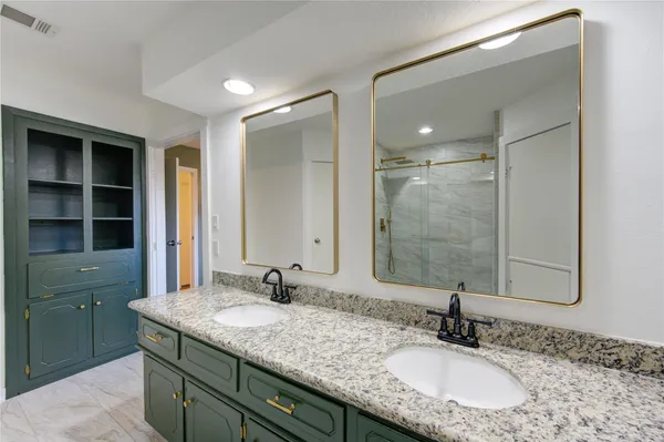 a bathroom with a granite countertop sink a mirror and shower
