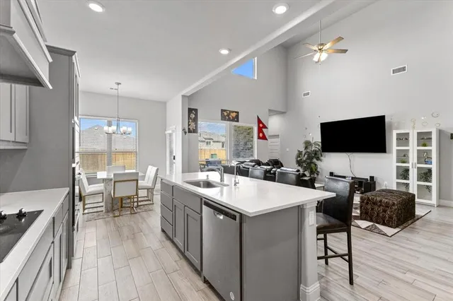 a living room with stainless steel appliances furniture a flat screen tv and a kitchen view