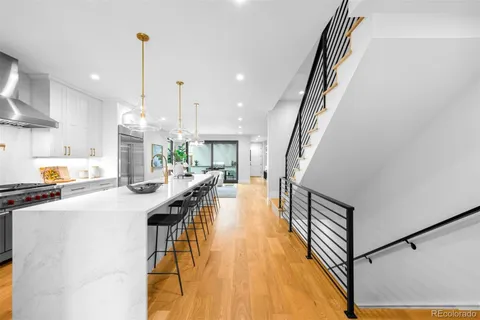 a kitchen with stainless steel appliances kitchen island granite countertop a refrigerator a stove and a wooden floors