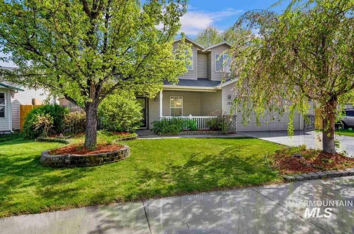 Obstructed view of property with covered porch, concrete driveway, a front lawn, and a garage