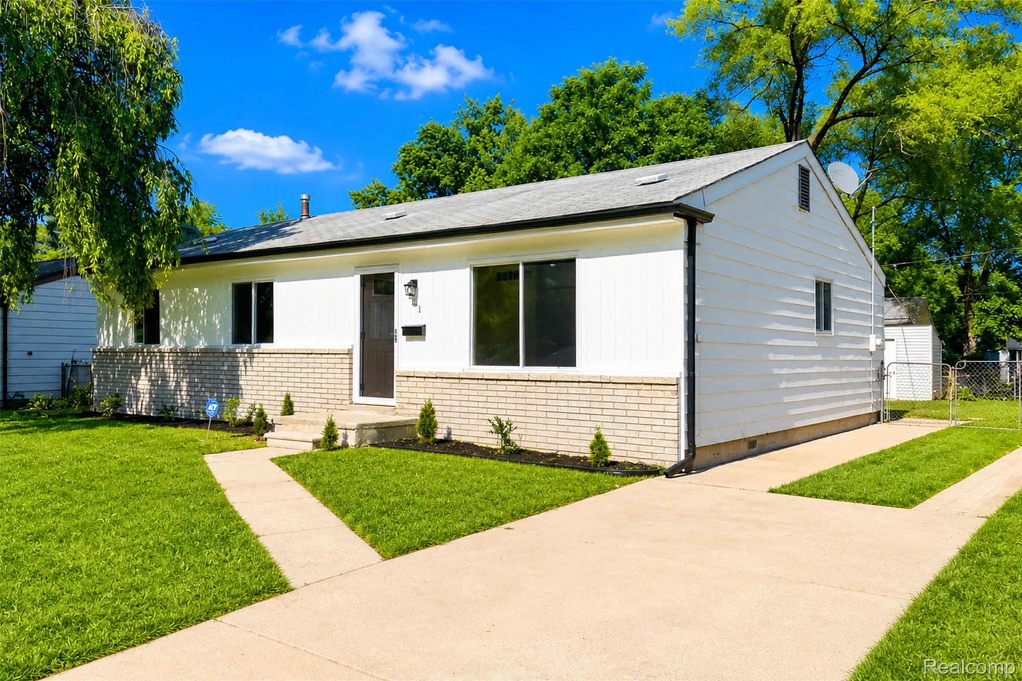 Contemporary ranch-style home featuring a white exterior with a light brick foundation