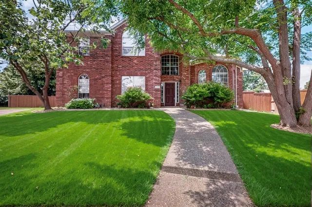 a view of a brick house next to a yard with big trees