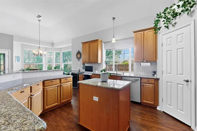 a kitchen with stainless steel appliances granite countertop a stove a sink dishwasher a refrigerator and a wooden cabinets