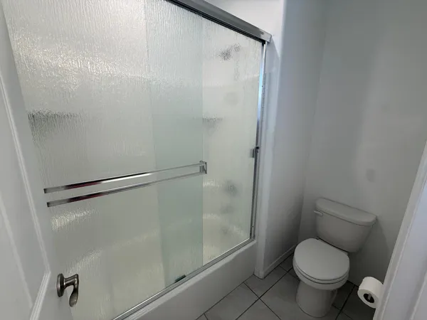 a white toilet sitting next to a shower