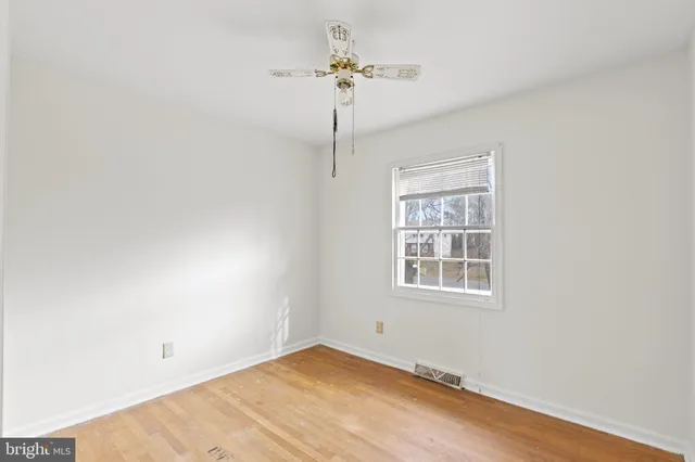 an empty room with a chandelier fan and windows